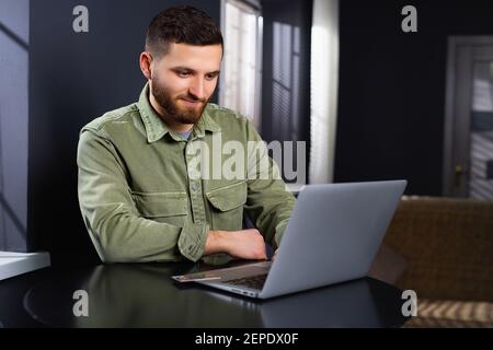 Young caucasian male businessman working at home using laptop. Telework. Work online. Stock Photo