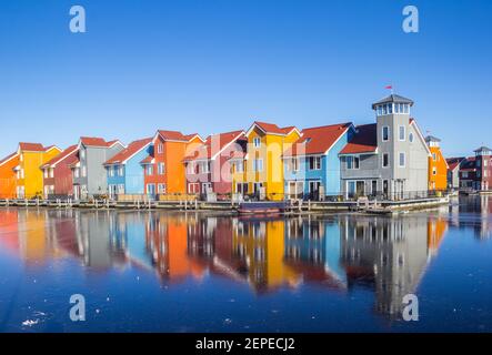 Colorful houses reflected in the frozen lake of Reitdiephaven in Groningen, Netherlands Stock Photo