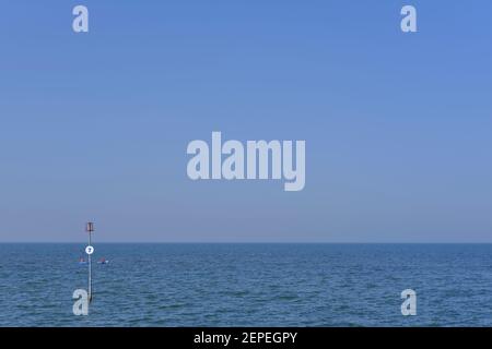 Marker at the end of a groyne in the North Sea on the Norfolk coast & two kayaks. Stock Photo