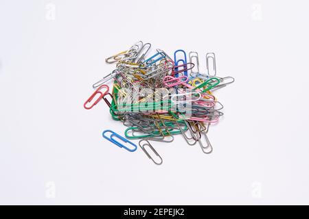 Isolated pile of plastic coated & metal paper clips anodised in colours. Paper clips on a white background isolated, some anodised metal. Stock Photo