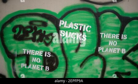 Street art on green black and grey painted background featuring stencil  "Plastic Sucks" And "There Is No Planet B" Slogan graffiti Stock Photo