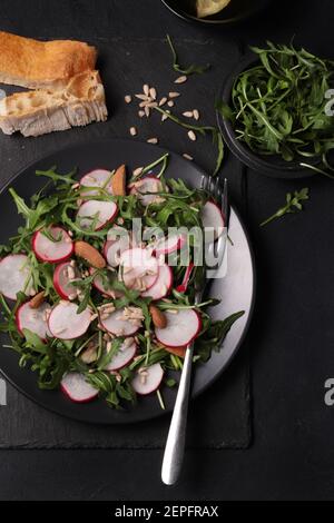 Fresh salad with rockets, radishes and almond on dark background. Healthy food. Stock Photo