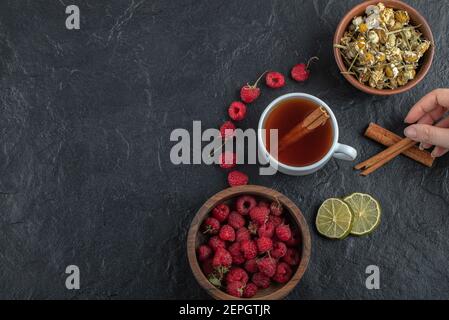Female hand holding cinnamon on black background Stock Photo