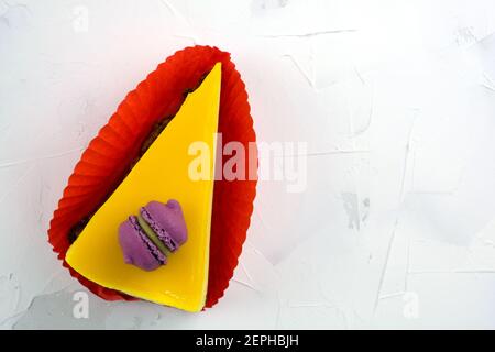 Cake with mango souffle on a white plate top view. Slice of cake with macaroon on top. Delicious dessert with mango. Stock Photo