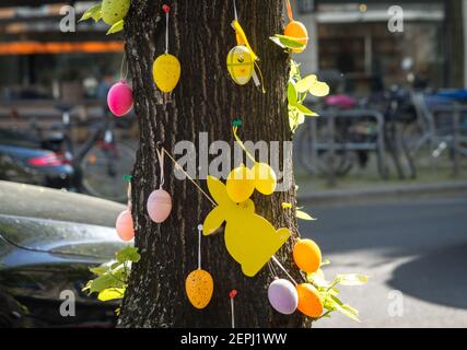 Easter decorations on city tree, Germany, colorful ornaments bringing seasonal cheer to an urban street Stock Photo