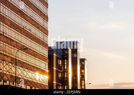 Old industrial architecture from the early 20th century and clear sky during sunset. Golden reflection of sun in windows. Red brick building exterior Stock Photo