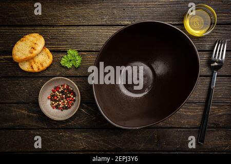 Empty plate for salad, condiments and spices on wooden kitchen table. Food cooking template concept. Top view with copy space. Flat lay Stock Photo