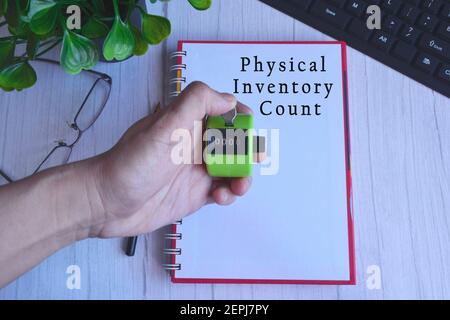 4 digit number hand tally counter clicker in male hand with text on notepad Stock Photo
