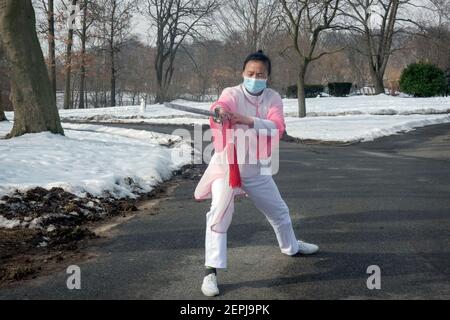 A middle aged Chinese American woman gracefully does Tai Chi dance exercises with a sword in a park in Flushing, Queens, New York City. Stock Photo