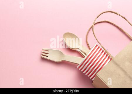 eco-friendly and disposable kitchenware template. composition with wooden spoons, forks, paper cups, paper package at pink coral background. flat lay. Stock Photo