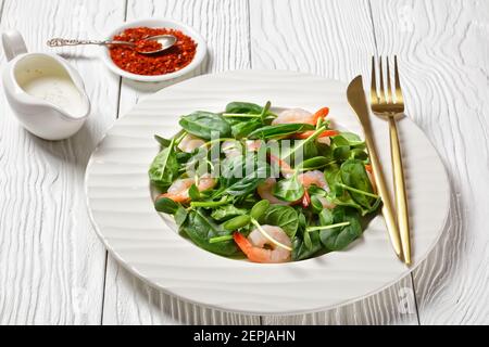 Salad of microgreens with avocado shrimps, baby spinach leaves, fresh sunflower sprouts, yogurt and tahini dressing with chili flakes served on a whit Stock Photo