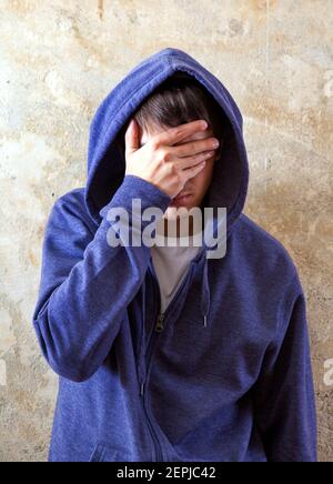 Sad Young Man in Hoodie by the Old Wall Stock Photo