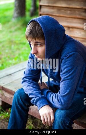 Sad Young Man in a Hoodie near the House outdoor Stock Photo