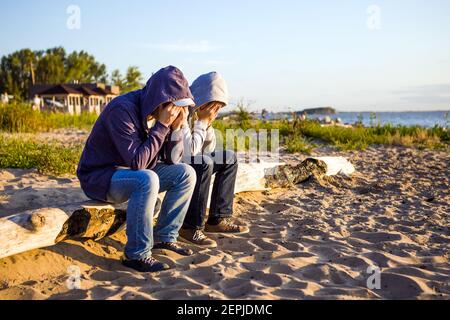 Two Sad Men sit on the Log at the Seaside Stock Photo