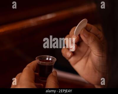 The image of a hand holding bread and wine During the Eucharist, Holy Communion in the church on sunday. Stock Photo