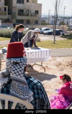 Due to COVID restrictions, Jewish women gather together in an open public garden, keeping distance and face masks, in order to read the scroll of Esther, customary during the Jewish holiday of Purim. Some wear customes, as it is one of the traditions of the holiday, together with the reading of the scroll and giving to the needy. Stock Photo