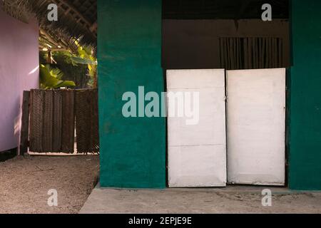 Mysterious entrance to the tropical garden. Colourful facade of holiday beach houses. Picturesque rural architecture, Zanzibar Island. Stock Photo