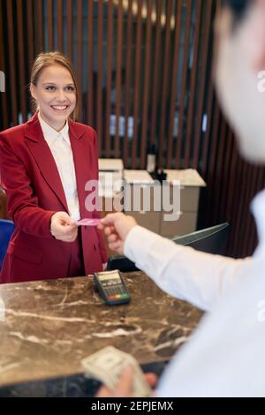 A pleasant female receptionist behind the counter receiving the guests at the hotel. Tourism, business, hotel Stock Photo