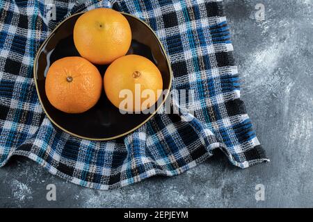 Three ripe oranges on black plate Stock Photo