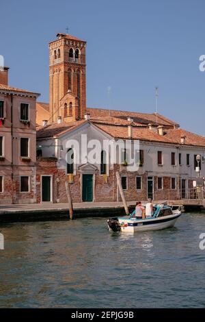 An Adult Couple on a Boat in Fondamenta Cannaregio canal with a Church Tower in the Background - Quiet Morning - Venice, Veneto, Italy Stock Photo