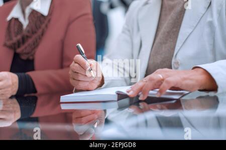 Business woman sitting at her workplace and making notes Stock Photo