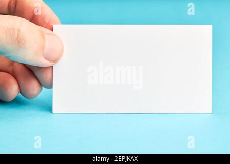 caucasian person holding business identity blank card over blue background. mockup for design Stock Photo