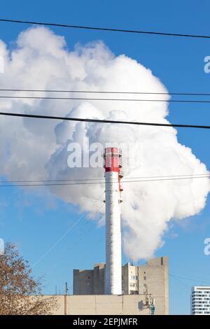 red-white chimneys of the boiler room, equipped with a traffic light. white smoke against blue sky on sunny frosty winter day Stock Photo