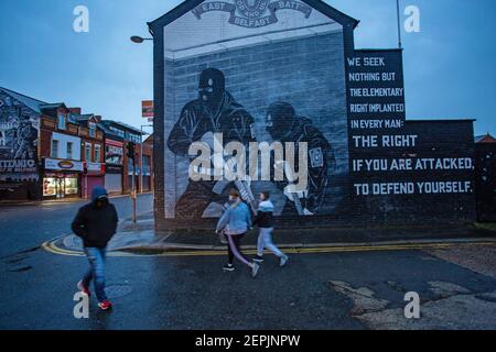BELFAST, NORTHERN IRELAND - February, 23: Pedestrians walking past a Loyalist paramilitary mural on the Newtownards road on February 23, 2021. Stock Photo