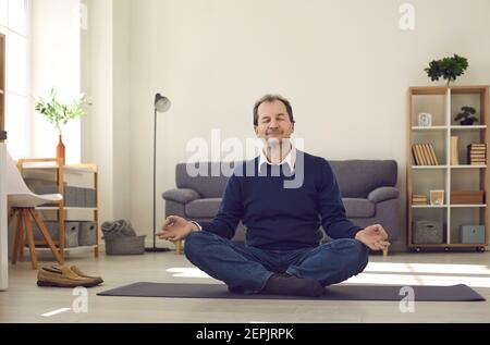 Man sitting on floor, meditating and enjoying moment of peace during busy work day Stock Photo