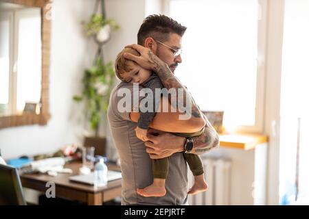 Dad putting to sleep baby boy in his arms at home Stock Photo