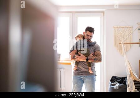 Dad putting to sleep baby boy in his arms at home Stock Photo
