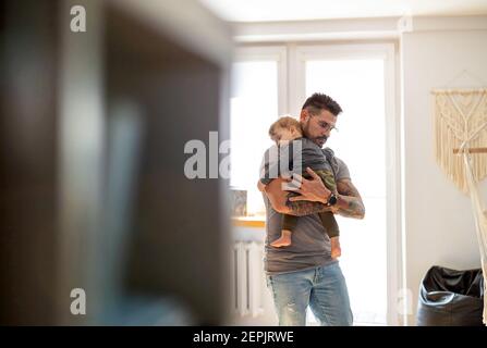 Dad putting to sleep baby boy in his arms at home Stock Photo