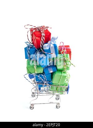 Trolley shopping cart filled with a lot of paper wrapped gift boxes on light background. Concept of online shopping, Christmas, presents for Valentine Day, Black Friday. CopySpace for text. Stock Photo