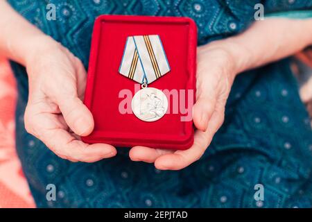 SAINT-PETERSBURG, RUSSIA - MARCH 8, 2020 Medal Victory 1945- 2020 World War II in old womans hands close up Stock Photo