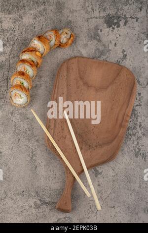 Breaded sushi hot rolls with wooden board and chopsticks Stock Photo