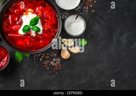 Culinary background with beetroot soup, sour cream and basil on a black concrete background. Stock Photo