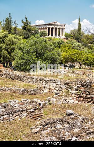 Ancient Greek ruins in Agora, Athens, Greece. Temple of Hephaestus, landmark of Athens in distance. Vertical scenic view of remains of famous classica Stock Photo