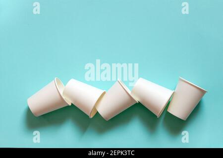 disposable white kraft paper cups stand on paper blue background Stock Photo