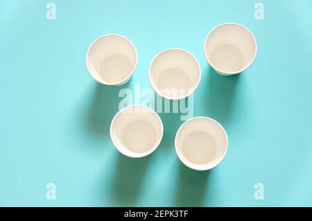 disposable white kraft paper cups stand on paper blue background Stock Photo