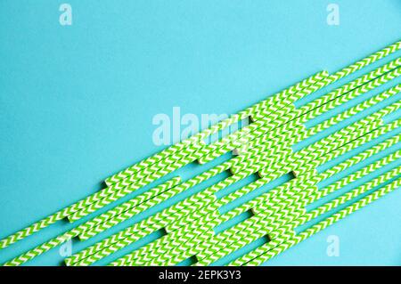 disposable green and white straws are laid out on a background of blue paper Stock Photo