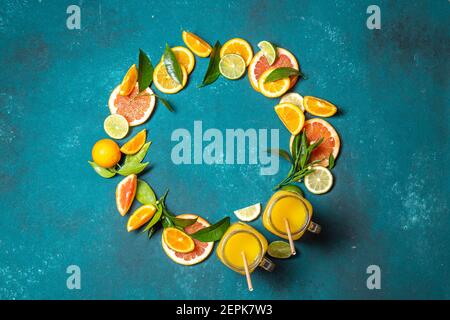 Citrus slices - orange,lemon and grapefruit with green leaves and citrus juice on blue background, frame, top view Stock Photo