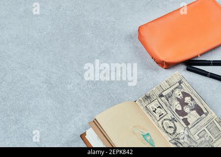 Comics book and orange pouch with pencils on gray background Stock Photo
