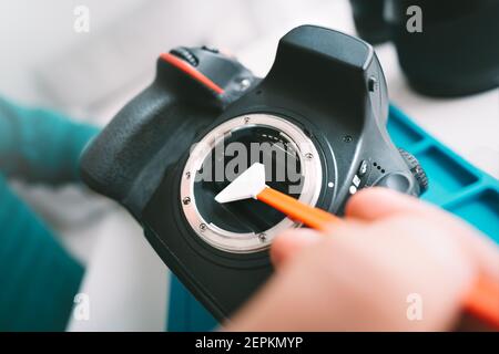 Close up of photographer hand cleaning sensor of his camera with camera sensor cleaner or cleaning swab. Photography equipment care Stock Photo
