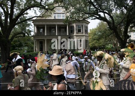 A vibrant second line parade marches past stately Uptown mansions in New Orleans, showcasing the city's cultural richness and community spirit. Stock Photo