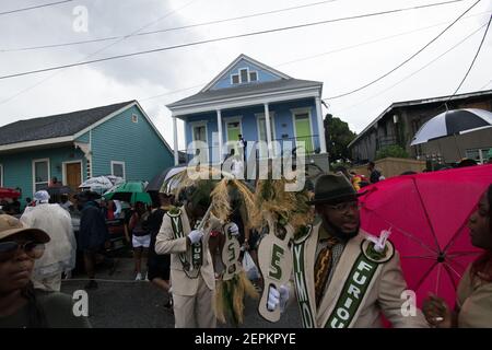 A vibrant second line parade marches past stately Uptown mansions in New Orleans, showcasing the city's cultural richness and community spirit. Stock Photo