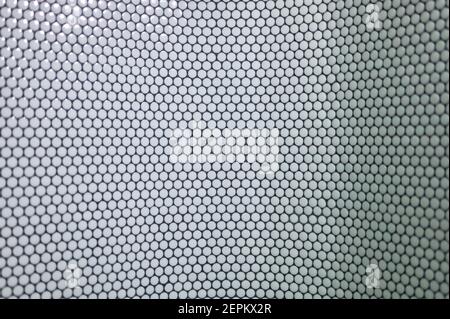 detail of a wall of round tiles on a black background in a public space Stock Photo