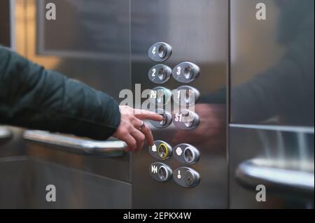 detail of a woman pressing a button on an elevator to go to a floor Stock Photo