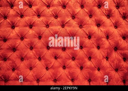 Close up background texture of scarlet red capitone genuine leather, retro Chesterfield style soft tufted furniture upholstery with deep diamond Stock Photo
