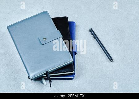 Three notebooks and a pen on a blue background. Flat lay Stock Photo