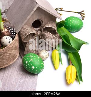 Easter banner with birdhouse, yellow tulips and Easter eggs. Natural decorations, low impact handmade decor from biodegradable materials and natural l Stock Photo